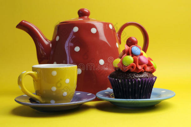五颜六色的糖果纸杯蛋糕配波尔卡圆点茶壶和茶杯。