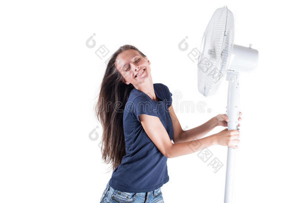 一个年轻的女人在白色<strong>背景</strong>下的冷风扇的风中凉快。