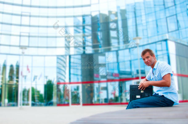 商务男士在现代化商务楼前带笔记本电脑