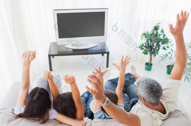 一家人在电视机前举起手臂