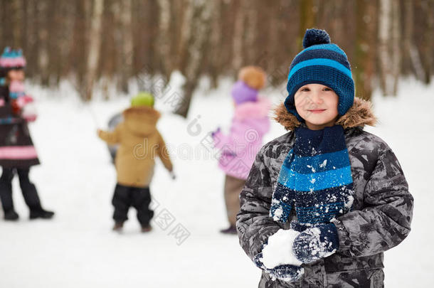 站在冬季公园里拿雪球的男孩的画像