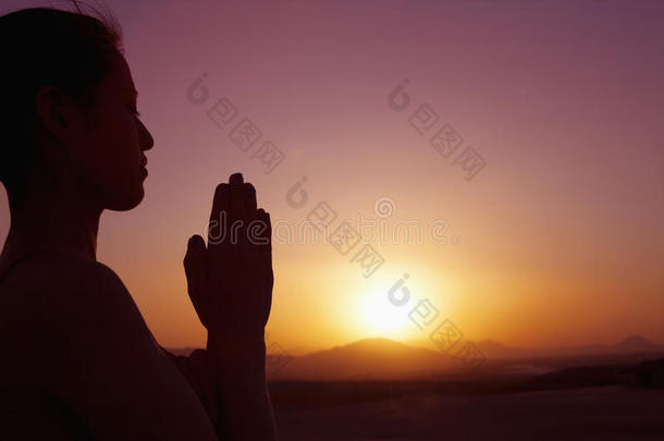 中国沙漠中双手合十祈祷的安详少女，侧影，落日，侧影