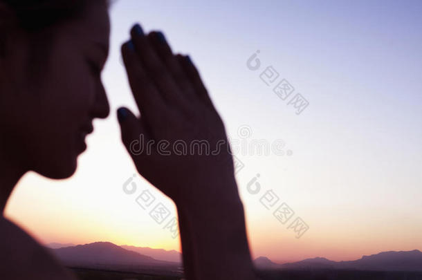 在中国的沙漠中，一个闭着眼睛双手合十祈祷的安详的年轻女子，专注于背景