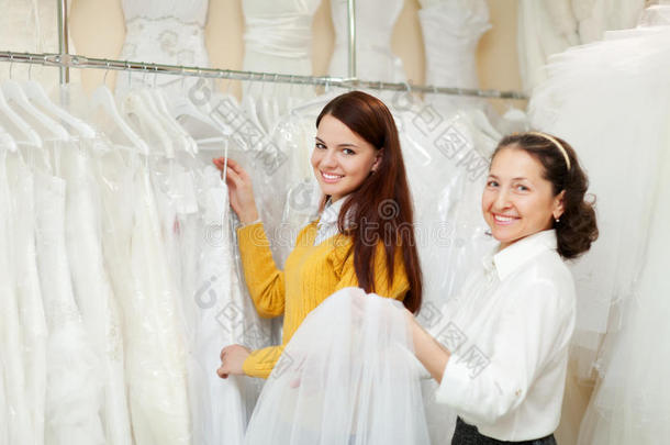 快乐的女人在婚纱店挑选婚纱。