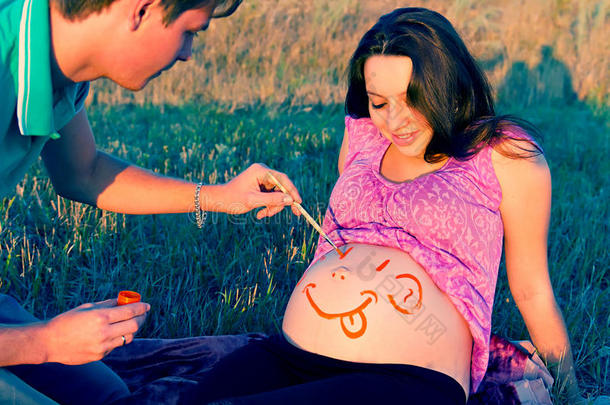 男人在孕妇肚子上画了一张脸