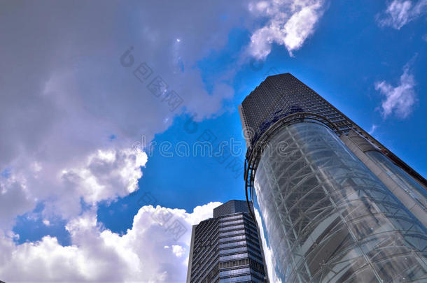 摩天大楼。仰望午间深蓝的天空，云彩和阳光普照