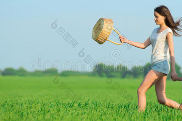 年轻快乐的女孩在绿色的麦田里跑巫婆篮子