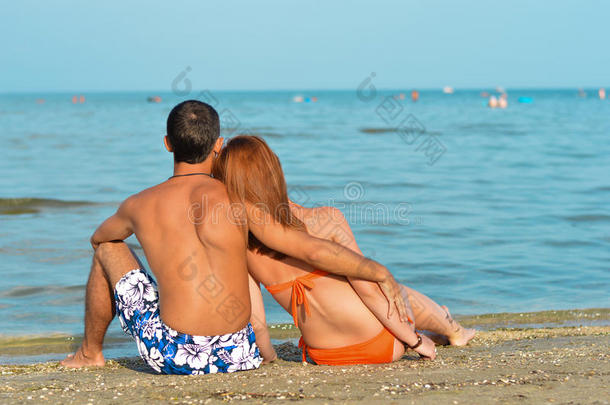 一对年轻夫妇<strong>坐</strong>在沙滩上<strong>拥</strong>抱