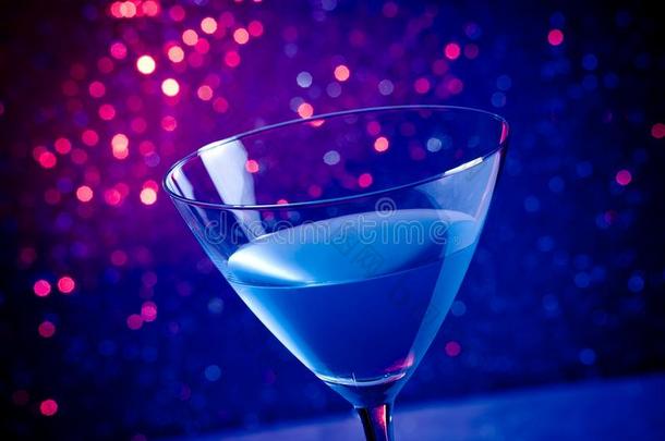 蓝紫光背景下的玻璃蓝鸡尾酒