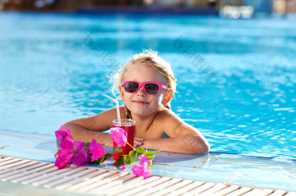 在游泳池里喝椰子汁的女孩