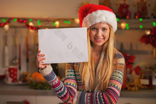 戴圣诞帽的微笑少女展示空白纸