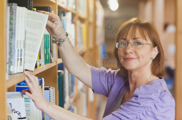 成熟的女图书管理员把一本书从书架上拿下来