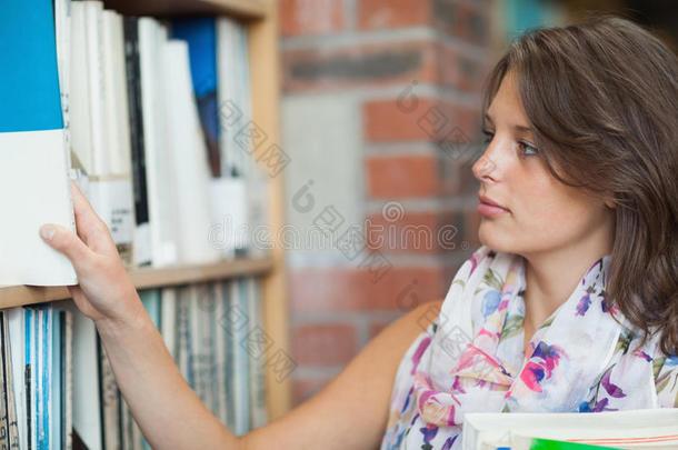 宝玛尔学生在图书馆书架上选书