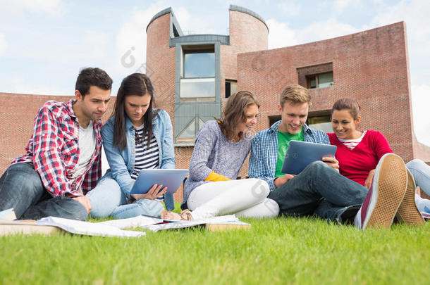 学生们在校园草坪上使用平板电脑