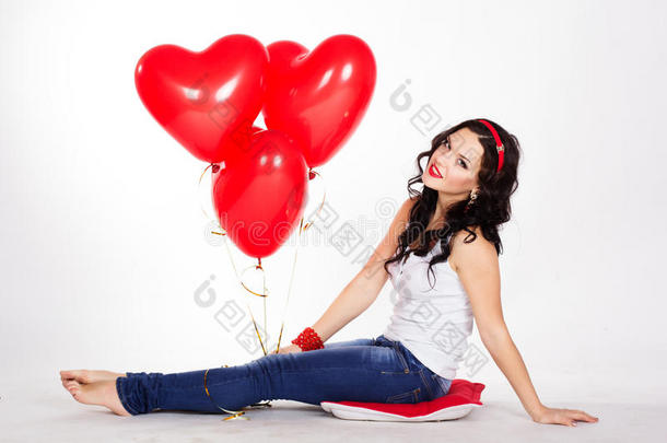 情人节美丽的年轻女子穿着牛仔裤，手持红色气球