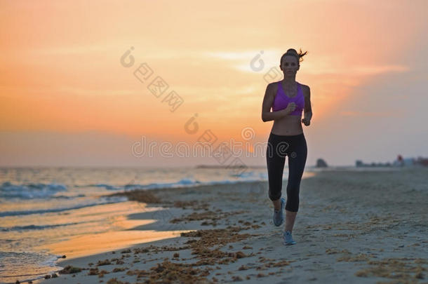 健身女青年晚上在沙滩上跑步