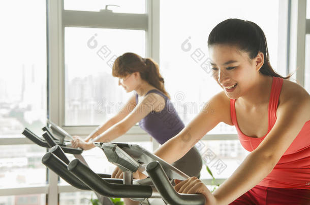 骑着固定自行车在健身房锻炼的年轻妇女