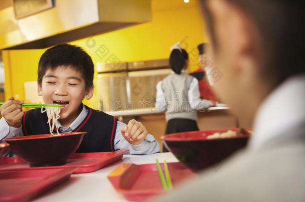 小学生在学校食堂吃面条