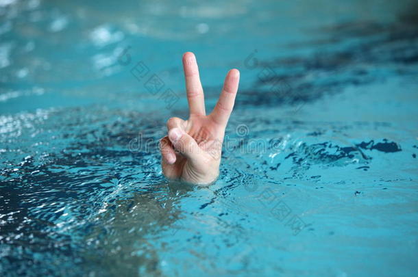 在水上用两个手指举起胜利或和平象征的手