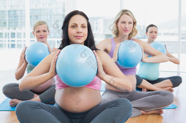 瑜伽课上快乐的孕妇抱着健身球