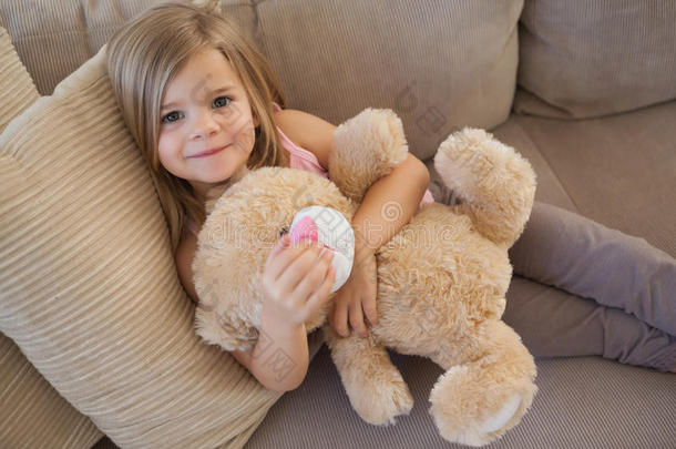 坐在沙发上的一个带着玩具的微笑女孩的画像
