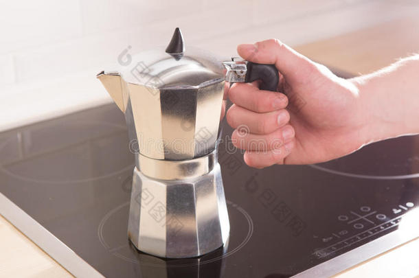 手拿意大利咖啡壶，放在黑色<strong>电饭锅</strong>上。