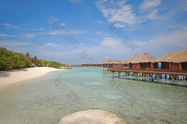 马尔代夫一个度假岛的蓝天碧绿水上豪华水上别墅与海滩相连