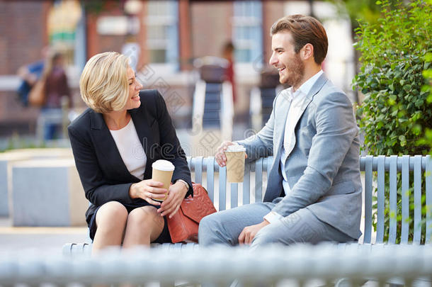 在公园长椅上喝咖啡的商务情侣
