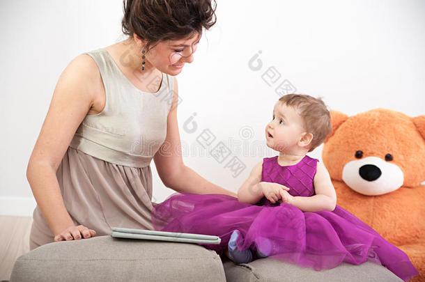 母亲和她好奇的女儿穿着紫罗<strong>兰色</strong>的衣服和泰<strong>迪</strong>熊