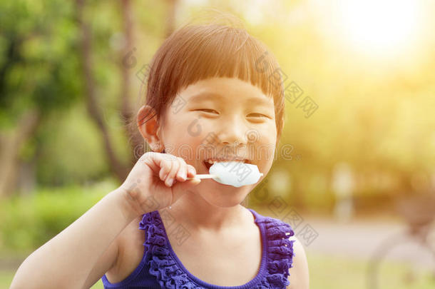 快乐的小女孩吃着落日背景的冰棍