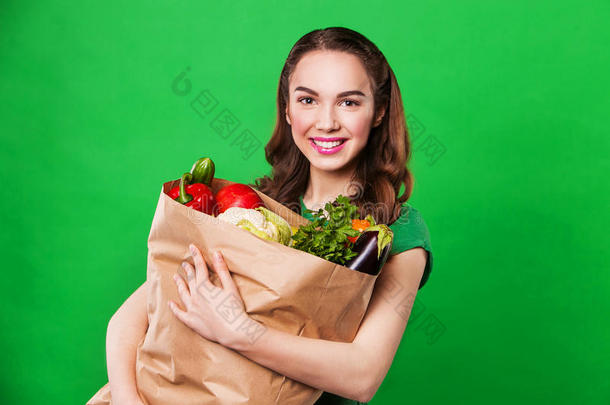 美丽的女人拿着一个装满新鲜健康<strong>食品</strong>的<strong>食品</strong>袋。看着摄像机