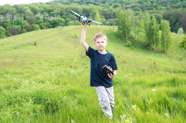 微笑的小男孩准备发射遥控飞机。美丽的自然背景。