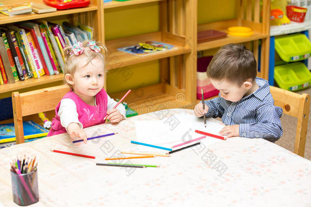 两个小朋友在桌边用彩色铅笔<strong>画画</strong>。小女孩和<strong>男孩画画</strong>