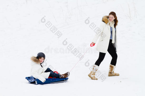 妈妈和儿子在雪地里的冬季公园里雪橇