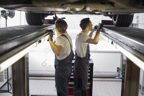 维修工程师在修理厂检查汽车的侧视图