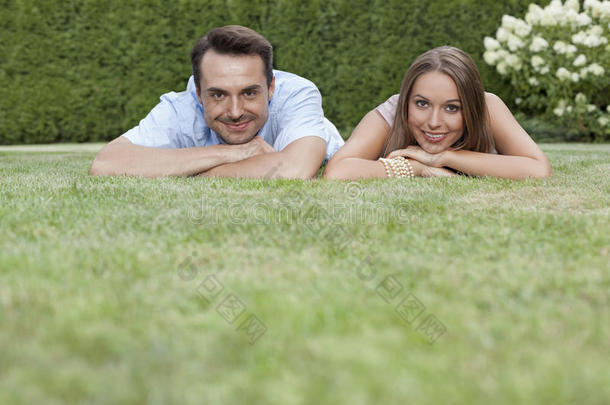一对微笑的年轻夫妇在公园的草地上放松