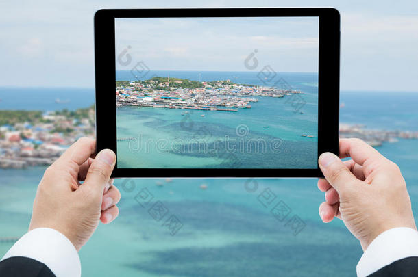 商人手拿平板电脑拍海滩和大海