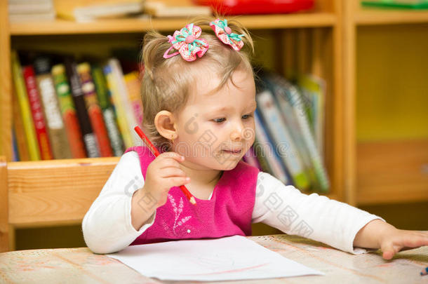 幼儿园的小女孩在桌边用彩色铅笔画画。幼儿园的小女孩