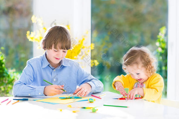 两个孩子画和剪彩色纸蝴蝶