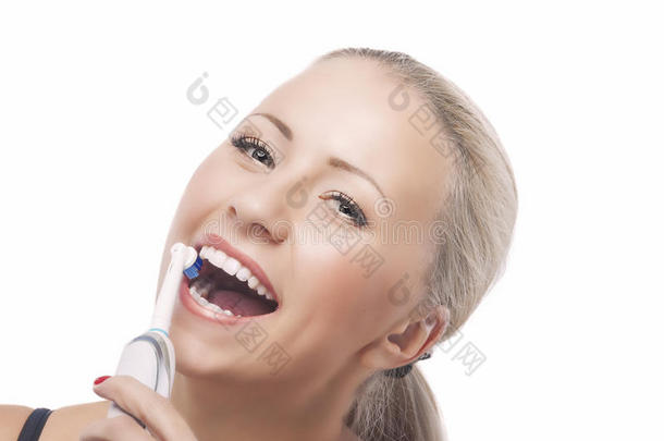 牙齿健康：金发白人妇女用电动牙刷刷牙
