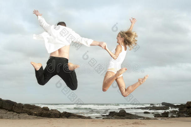 快乐的年轻夫妇在海滩上欢蹦乱跳