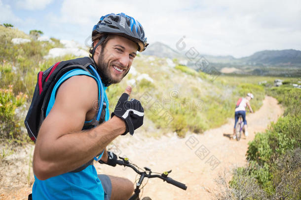 合身情侣骑自行车在山路上男人微笑着对着镜