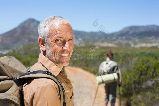 徒步旅行的情侣走在山路上男人对着镜头微笑