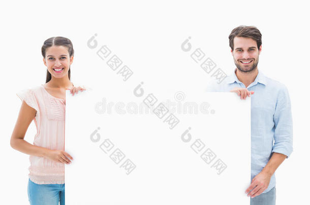 迷人的年轻夫妇拿着<strong>海报</strong>对着镜头微笑