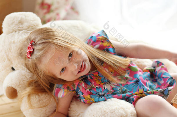 漂亮的小女孩躺在柔软的大玩具熊上