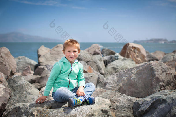 可爱的小男孩坐在大石头上