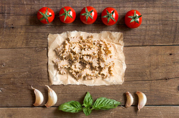 意大利面，西红柿，大蒜和罗勒在木质背景上