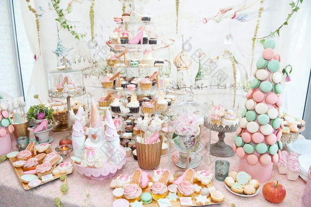 婚礼装饰有柔和的彩色纸杯蛋糕、蛋白酥皮、松饼和麦卡龙蛋糕