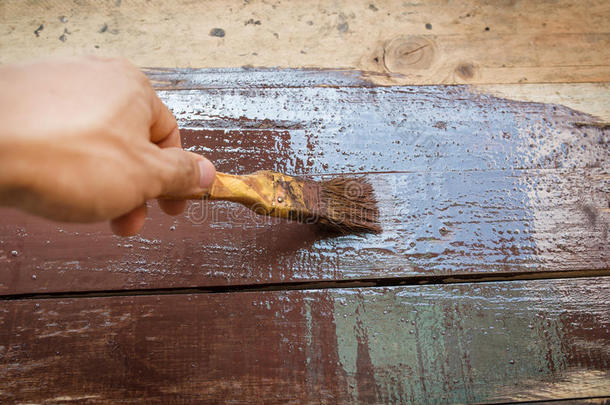 用棕色油漆和刷子染色的木板栅栏