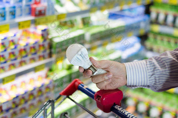 男的或女的手持节能二极管灯泡灯泡在超市，diy百货公司手推车